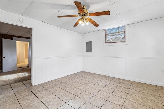 empty room with a drop ceiling, electric panel, and ceiling fan