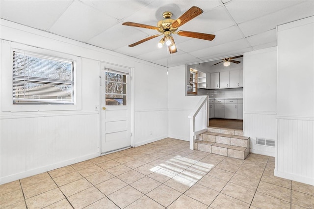 tiled foyer featuring ceiling fan and a drop ceiling