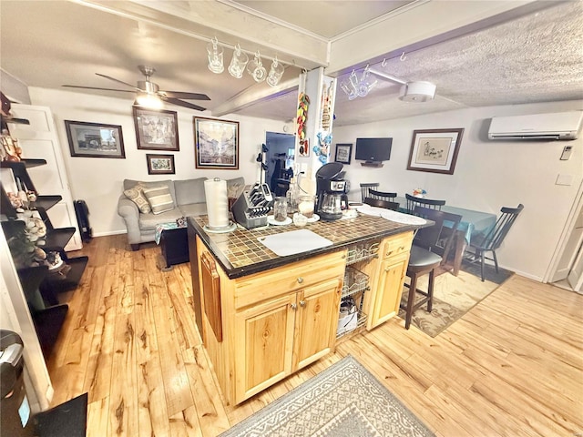 kitchen featuring a wall mounted air conditioner, tile countertops, light hardwood / wood-style flooring, and a textured ceiling