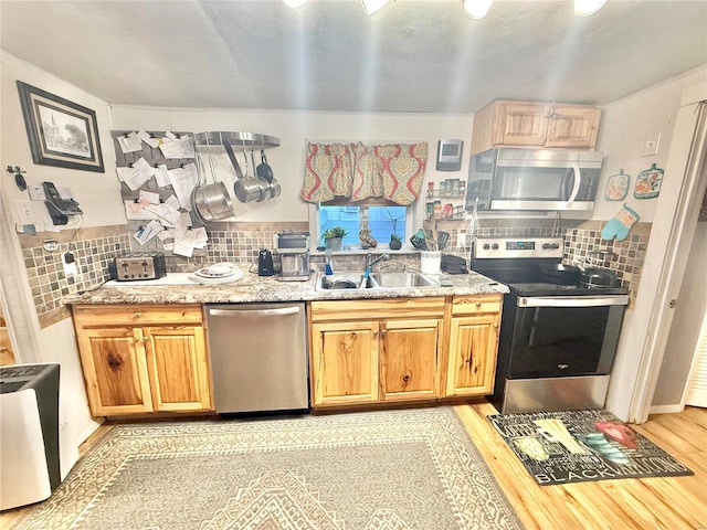 kitchen featuring appliances with stainless steel finishes, light hardwood / wood-style floors, sink, and backsplash