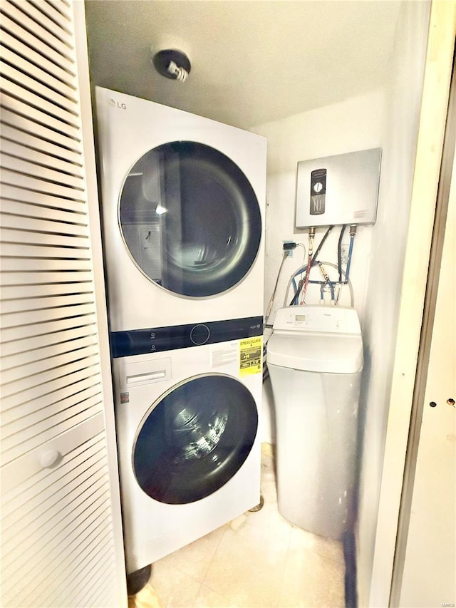 laundry area featuring stacked washer / drying machine and light tile patterned floors