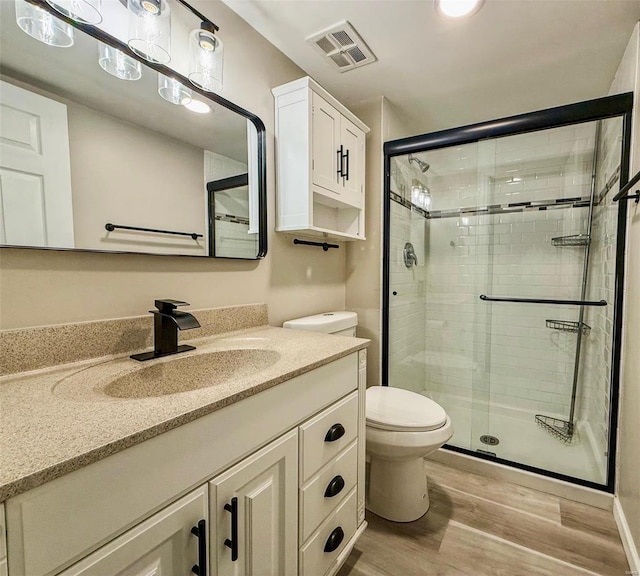 bathroom with visible vents, a shower stall, toilet, and wood finished floors