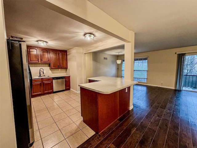 kitchen featuring appliances with stainless steel finishes, light countertops, a sink, and decorative backsplash