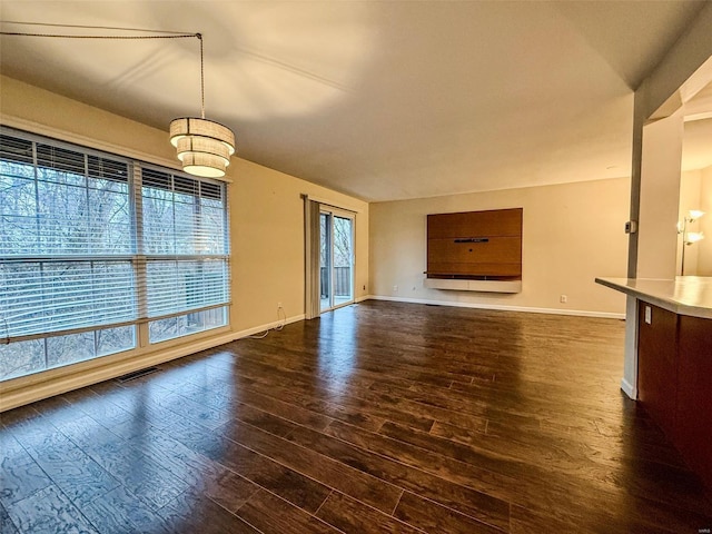 unfurnished living room with dark wood-type flooring, visible vents, and baseboards