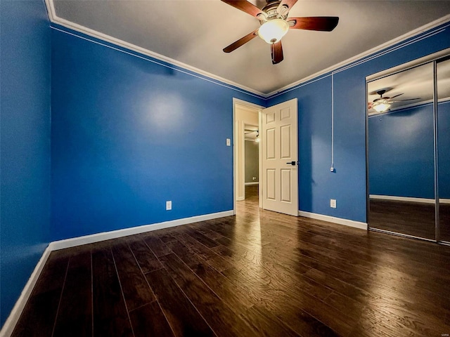 unfurnished bedroom with baseboards, a ceiling fan, wood finished floors, crown molding, and a closet