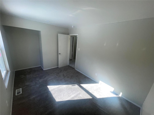 unfurnished room with dark colored carpet