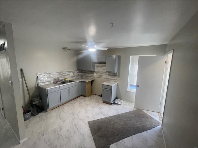 kitchen featuring backsplash, ceiling fan, sink, and gray cabinetry