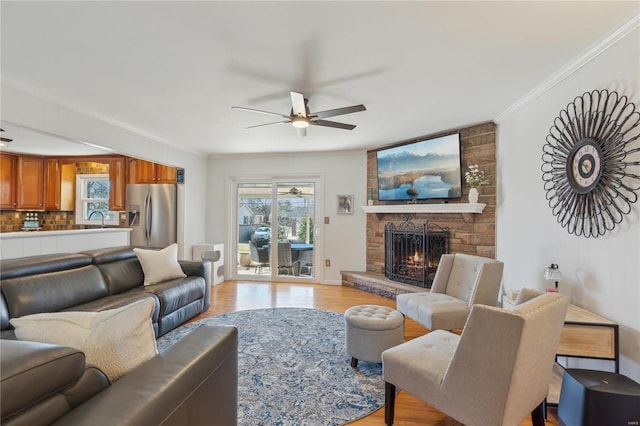 living room with light wood-style floors, a fireplace, a wealth of natural light, and crown molding