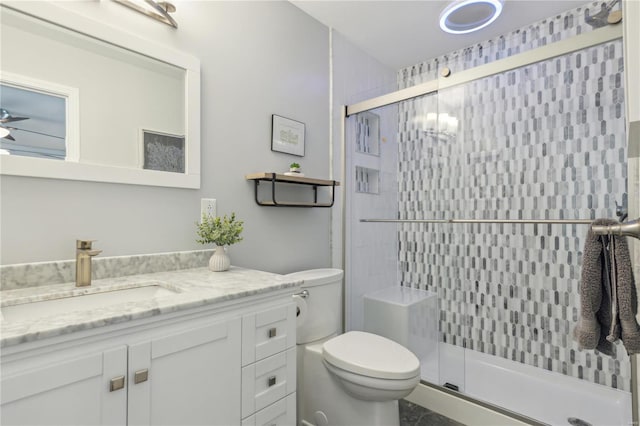 bathroom with ceiling fan, a stall shower, vanity, and toilet