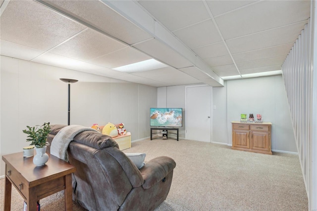 living area featuring carpet and a paneled ceiling