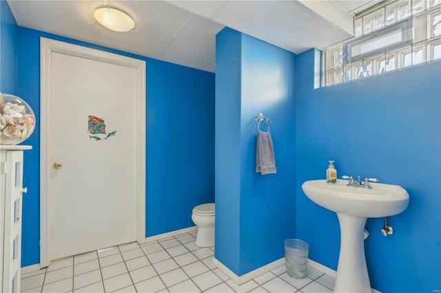 bathroom featuring toilet, tile patterned flooring, baseboards, and a sink