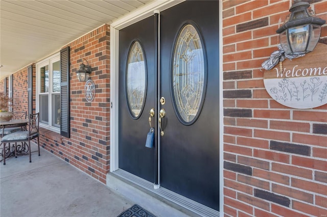 property entrance featuring covered porch and brick siding