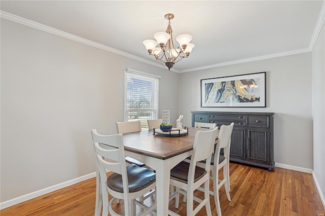 dining room featuring a chandelier, baseboards, crown molding, and light wood finished floors