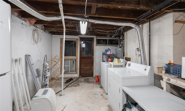 basement featuring gas water heater, washing machine and dryer, and white refrigerator