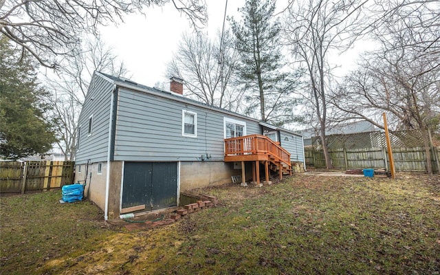 rear view of house featuring a wooden deck and a lawn