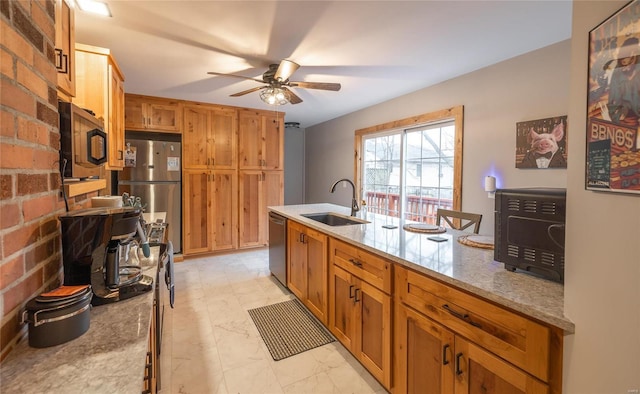 kitchen with light stone counters, ceiling fan, stainless steel appliances, and sink