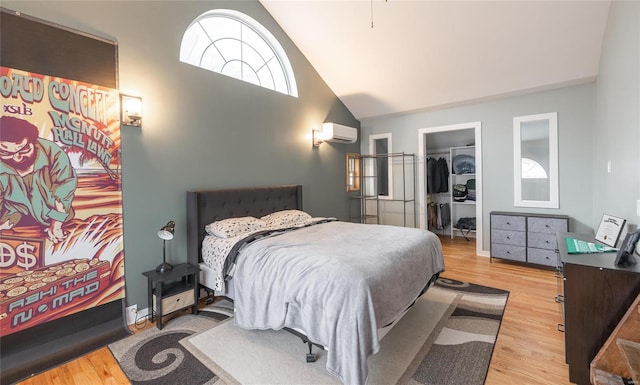 bedroom featuring light hardwood / wood-style flooring, high vaulted ceiling, a wall mounted air conditioner, a walk in closet, and a closet