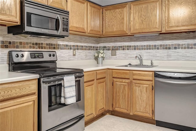 kitchen with light tile patterned floors, stainless steel appliances, tasteful backsplash, light countertops, and a sink