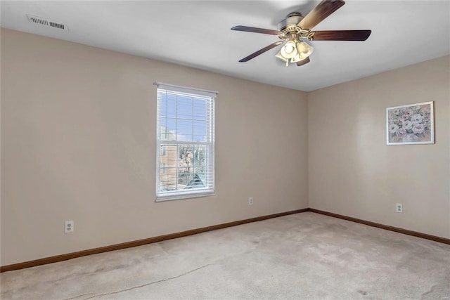 spare room featuring light carpet, ceiling fan, visible vents, and baseboards