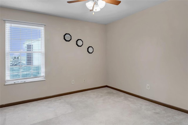 unfurnished room featuring light carpet, ceiling fan, baseboards, and a wealth of natural light