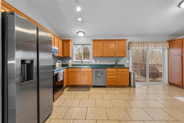 kitchen featuring lofted ceiling, sink, a textured ceiling, light tile patterned floors, and appliances with stainless steel finishes