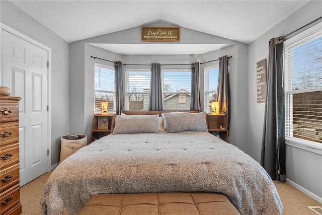 bedroom featuring lofted ceiling, carpet floors, and a textured ceiling