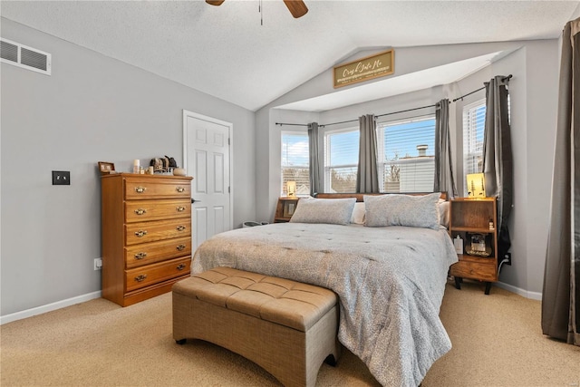 bedroom with ceiling fan, vaulted ceiling, light colored carpet, and a textured ceiling