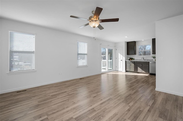 unfurnished living room featuring ceiling fan, sink, and light wood-type flooring