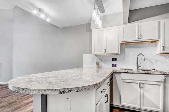 kitchen with sink, tasteful backsplash, decorative light fixtures, kitchen peninsula, and white cabinets