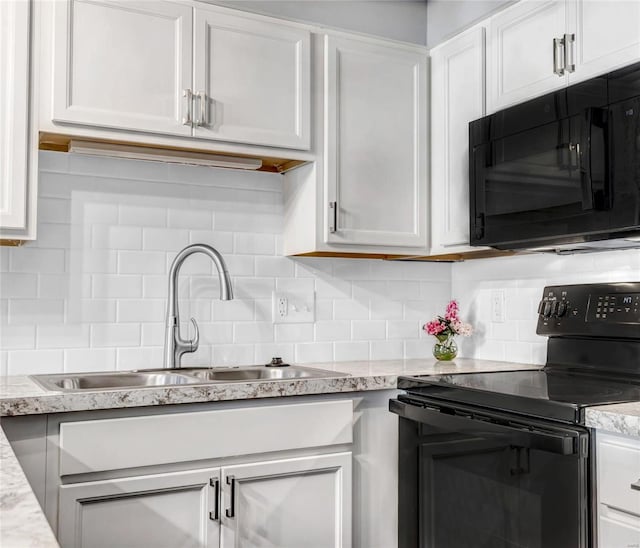 kitchen with sink, light stone counters, black appliances, decorative backsplash, and white cabinets