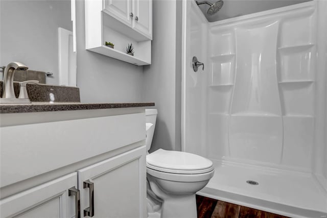 bathroom featuring wood-type flooring, toilet, vanity, and a shower