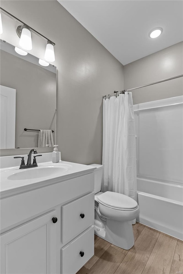 full bathroom with wood-type flooring, toilet, shower / bathtub combination with curtain, and vanity