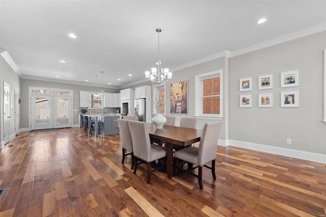 dining room featuring an inviting chandelier, hardwood / wood-style floors, ornamental molding, and sink