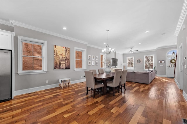 dining space with hardwood / wood-style flooring, crown molding, and ceiling fan with notable chandelier