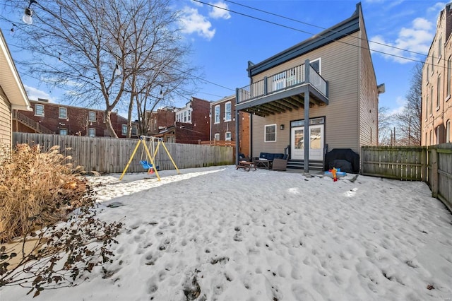 snow covered property featuring a balcony and a playground