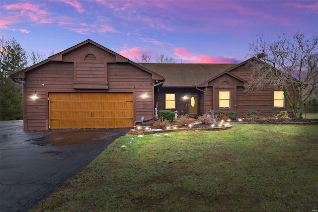 single story home featuring a garage and a lawn