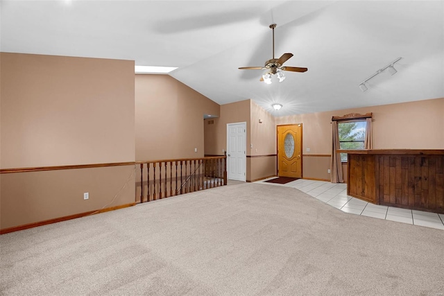 spare room with light carpet, vaulted ceiling, rail lighting, and ceiling fan