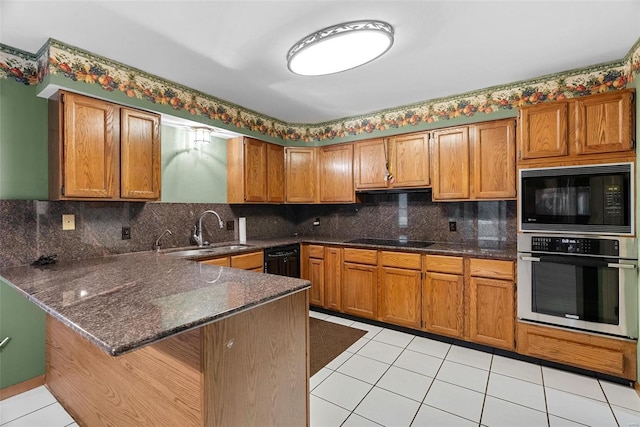 kitchen with sink, a breakfast bar, tasteful backsplash, black appliances, and kitchen peninsula