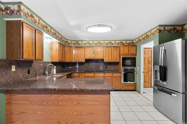 kitchen featuring sink, light tile patterned floors, black appliances, decorative backsplash, and kitchen peninsula