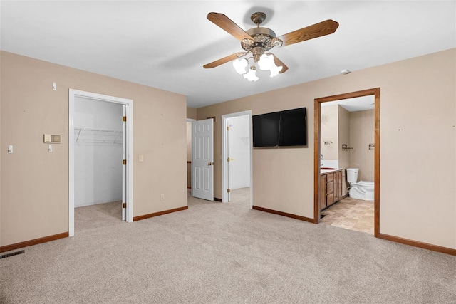 unfurnished bedroom with a spacious closet, light colored carpet, ensuite bath, and a closet