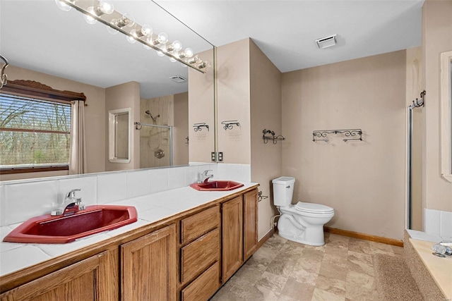 bathroom featuring vanity, a shower with shower door, and toilet