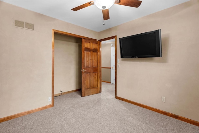 unfurnished bedroom with light colored carpet, a closet, and ceiling fan