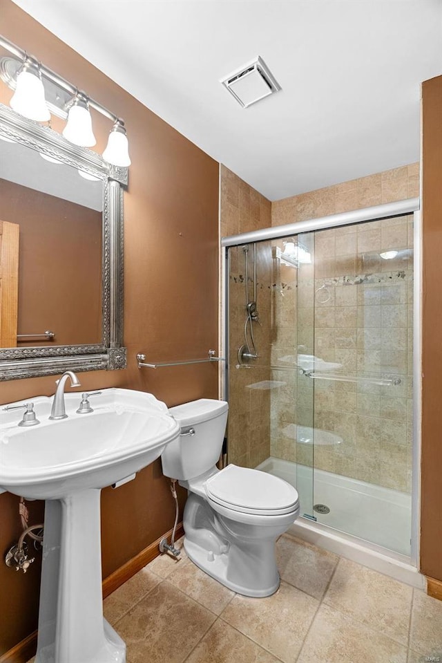 bathroom with sink, tile patterned floors, a shower with door, and toilet