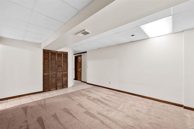 basement featuring light carpet and a drop ceiling