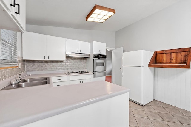 kitchen with sink, white appliances, light tile patterned floors, white cabinets, and vaulted ceiling