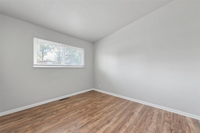 spare room featuring lofted ceiling and dark hardwood / wood-style floors