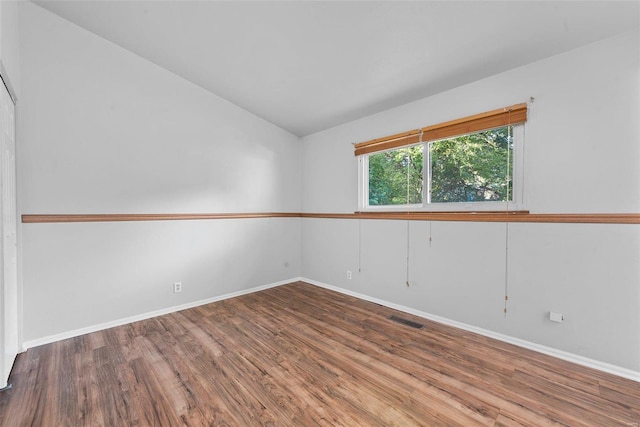 unfurnished room with lofted ceiling and hardwood / wood-style floors