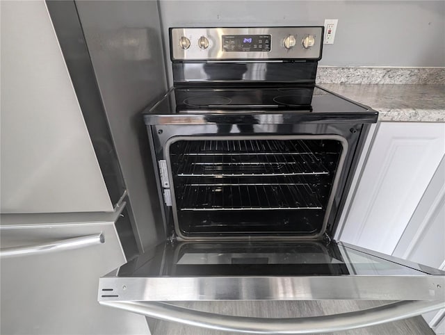 interior details featuring stainless steel range with electric stovetop and white cabinets