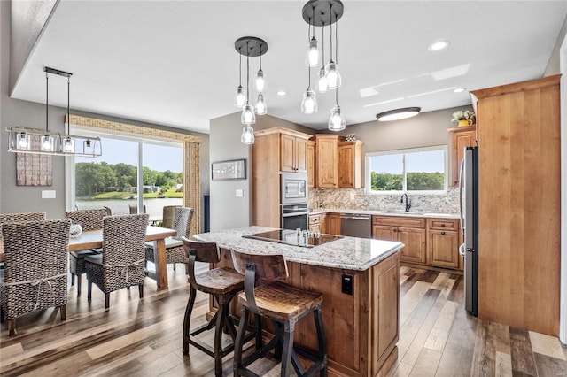 kitchen featuring appliances with stainless steel finishes, hanging light fixtures, hardwood / wood-style floors, tasteful backsplash, and a kitchen island