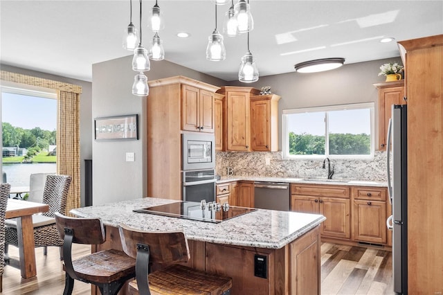 kitchen with sink, a center island, appliances with stainless steel finishes, pendant lighting, and decorative backsplash